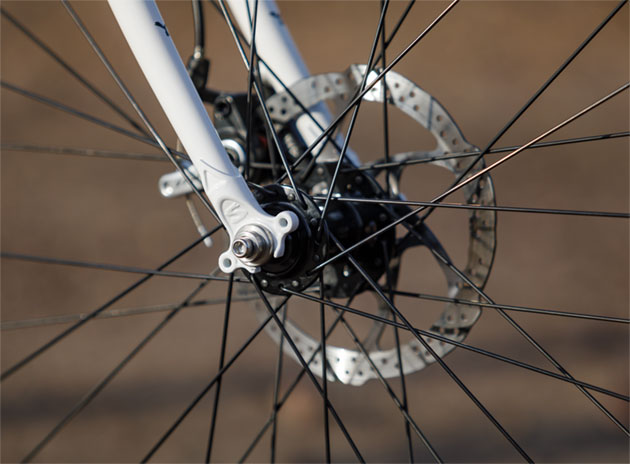 Zoom in right side front view of the lower fork, front axle and brake disc of a Surly Midnight Special bike