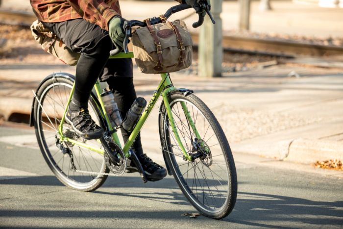 A cyclist shown from the waist down leans into a right turn while riding a Surly Disc Trucker bike