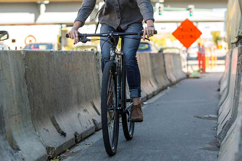 Urban commuter cyclist riding in jeans through road construction path