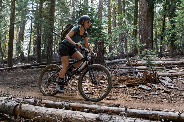 Mountain biker with gray helmet riding black Surly Karate Monkey in the woods