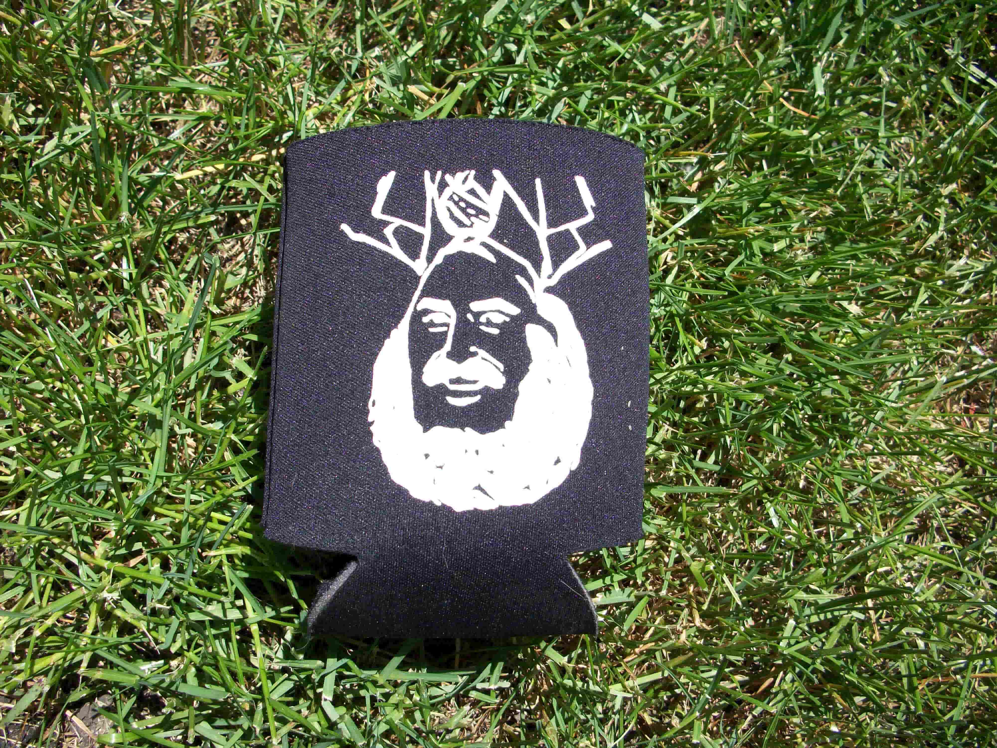 Downward view of a flattened, black Surly can cooler with a white graphic, laying in grass