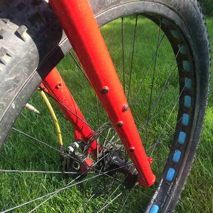 Right side downward cropped view of the front fork with wheel assembly on a Surly Krampus bike, red