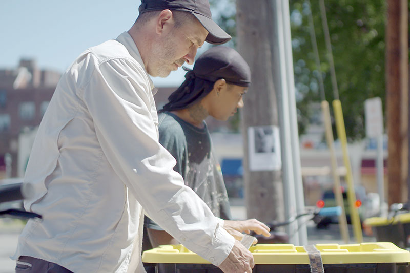 Two people loading containers with supplies for deliever by bike