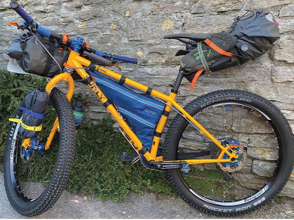 Yellow Surly Karate Monkey with handlebar bag, frame bag, seatpack, and gear mounted on fork blades