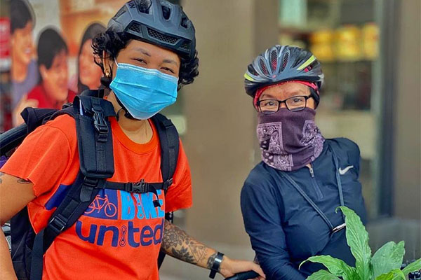 Aneka with mother on bike in city wearing face coverings