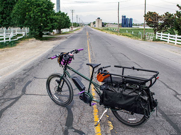 Surly Big Easy decked out with custom parts, purple pedals and grips, parked in middle of street