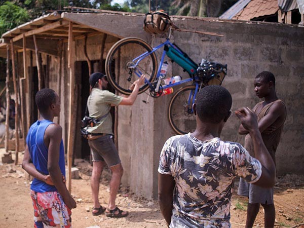 People standing outside, person working on Midnight Special bike hanging next to building