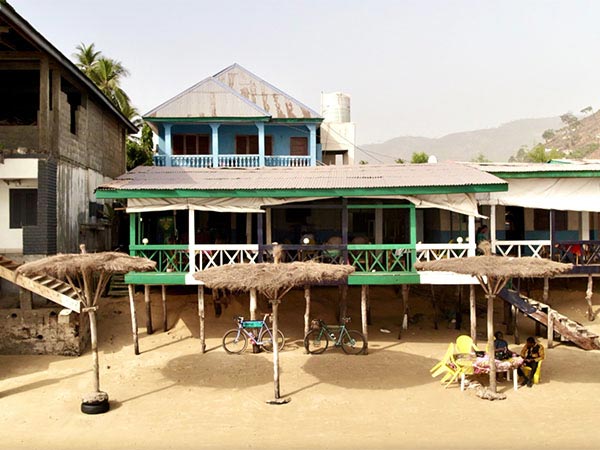  Beach front homes on stilts, bikes parked out front, people sitting at table