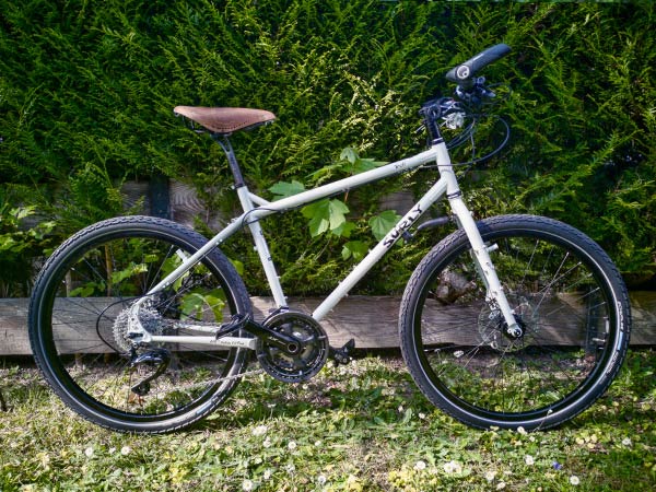 Troll bike built with no racks, bags, or bottle cages yet, parked outside again wood fence