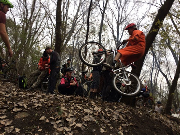 Cyclist in orange jumpsuit catching air off jump while people watch