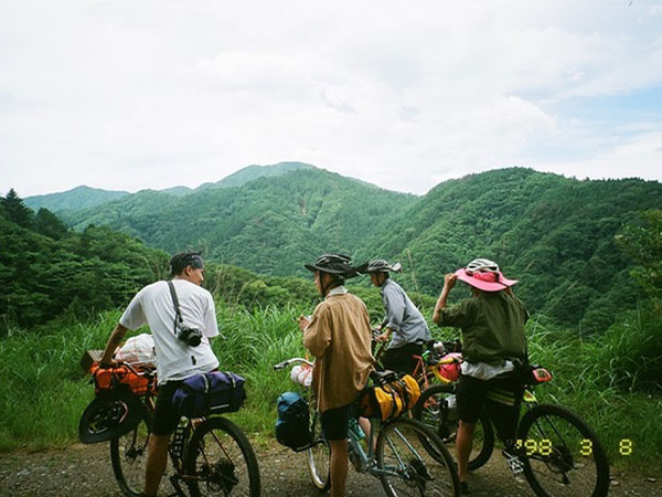 Four cyclists standing over bikes stopped, bikes loaded for bikepacking