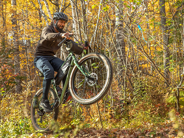 Person riding Grappler on forest trail pulling wheelie