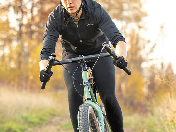 Person riding Grappler off-road in forest, hands in the drops of the handlebar