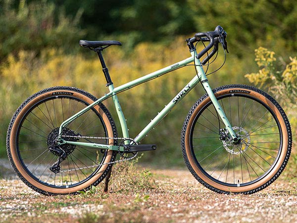 Surly Grappler bike side view, propped up on double-track road, wildflowers and plants in background