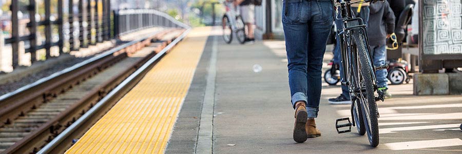 Cyclist with backpack and helmet walking bike to commuter train stop