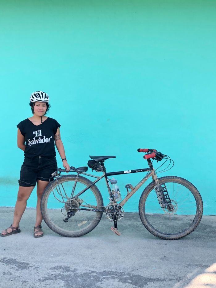 Andrea posing with her bike in front of a blue wall