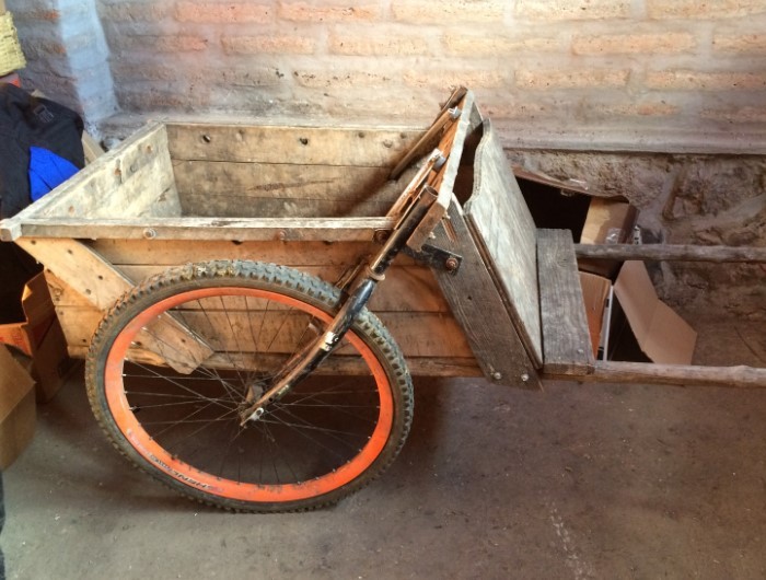 A custom made wheelbarrow against a stone wall