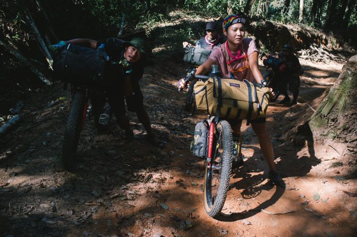 Immu at Mae Chan Tai walking her bike up a hill