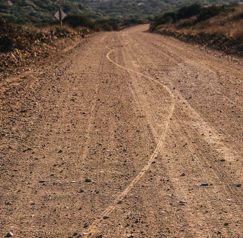 Rural gravel road on sunny day with bike track left in it