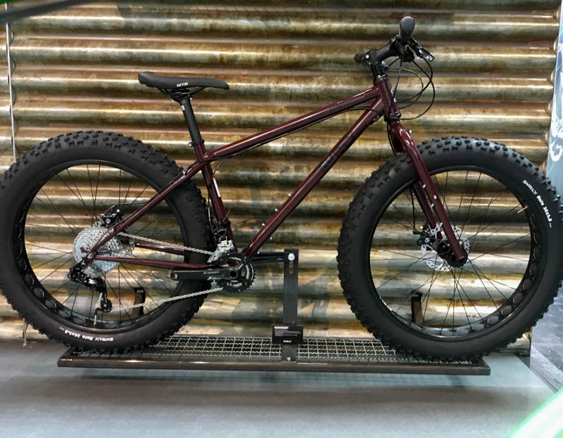 Right profile of a Surly Wednesday MY17 fat bike, Bum Wine Red, parked in front of a steel wall 