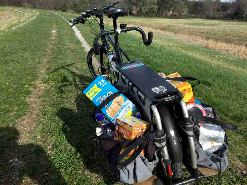 Rear view of a Surly Big Dummy bike, facing down a grassy road between 2 fields