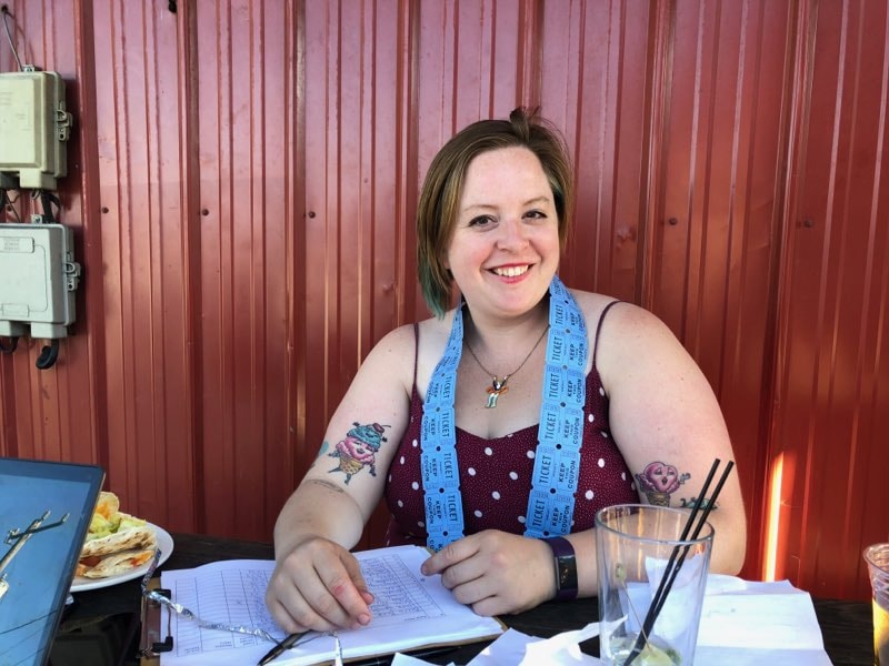 Smiling Marley sits a table with a ticket strip draped over shoulders with a clipboard while dining