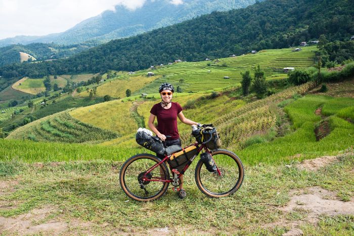 Immu standing with her bike against a beautiful green space background