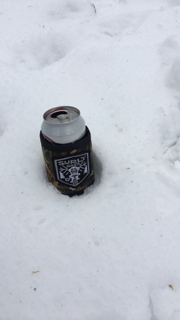 Surly can cooler with a beverage in it, sitting on snow