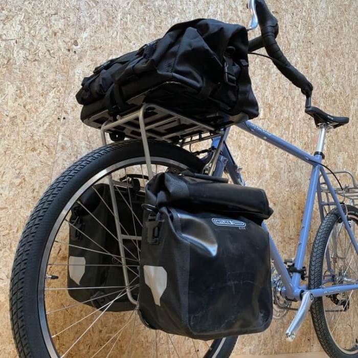 Front upward view of a light blue Surly bike with front saddle bags and Surly TV Tray rack with gear pack on top