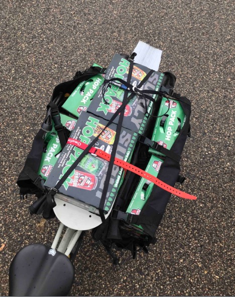 Downward view of bike rear saddlebags and rack loaded with Surly beer on a bike with a black seat