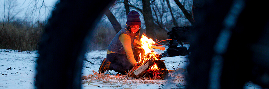 Person lighting a camp fire before sunset