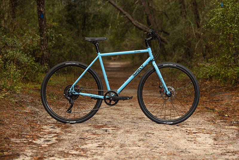 Surly Preamble blue flat bar bike side view on forest trail