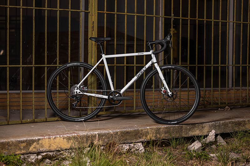 Surly Preamble white drop bar bike side view in front of fence