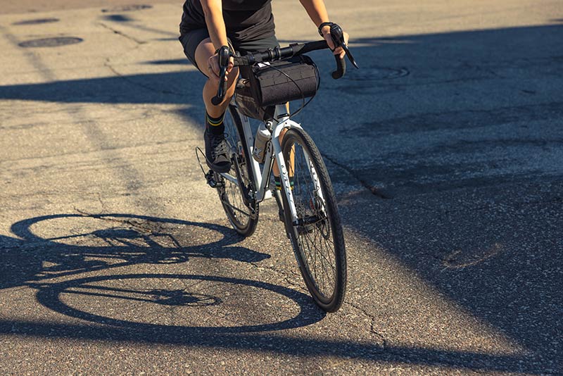 Person riding Surly Preamble white drop bar bike on street focus on bike