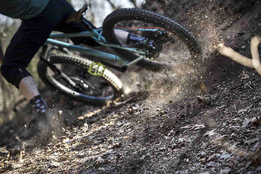 Rear cropped view of cyclist on a Surly Wednesday bike, skidding to the left on a dirt trail