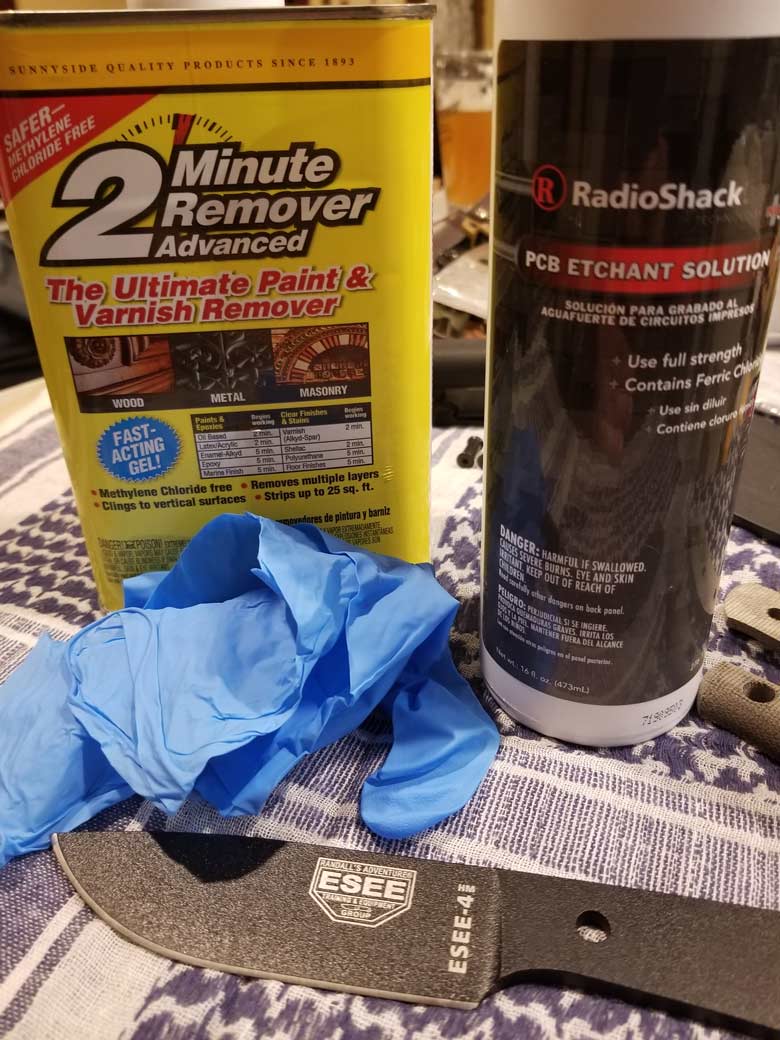 Can of paint and varnish remover, bottle of PCB etchant solution, black knife blade and nitrile gloves on woven blanket