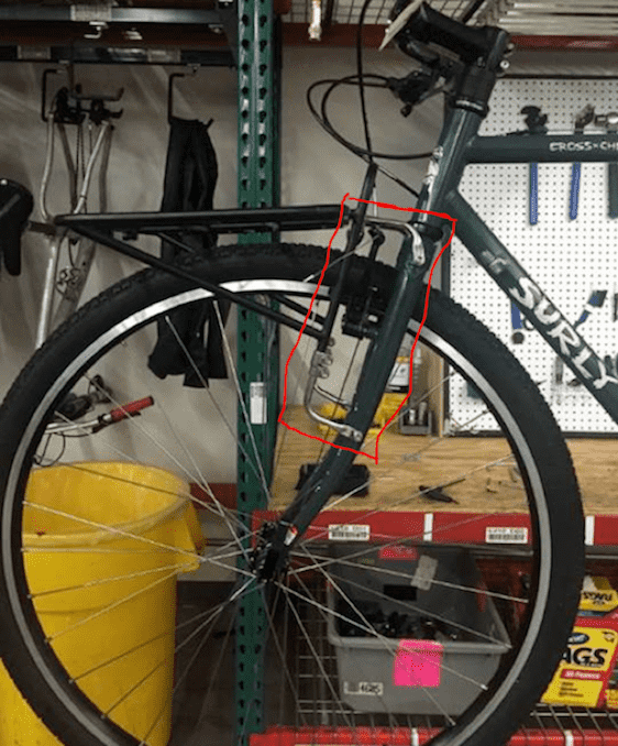 Left profile view of the front a Surly Cross Check bike on work table, with a Pack Rack mount to the forks